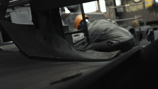 Worker transporting waste from work to a conveyor belt in a factory