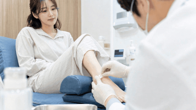 Doctor wiping female patient's feet with antiseptic swab