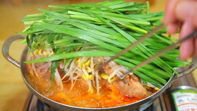 Chopsticks taking meat out of pork backbone stew with chives and bean sprouts