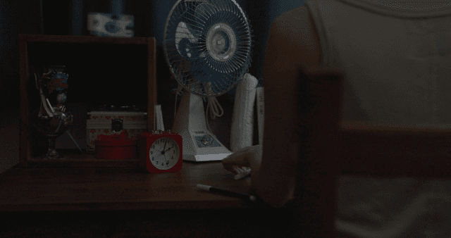 책상에 앉아 있는 사람과 선풍기