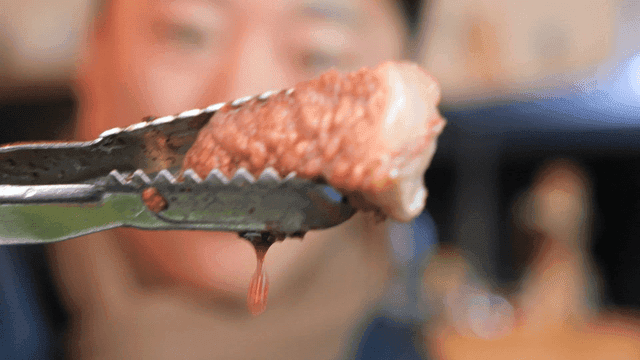 Piece of cooked beef held with tongs