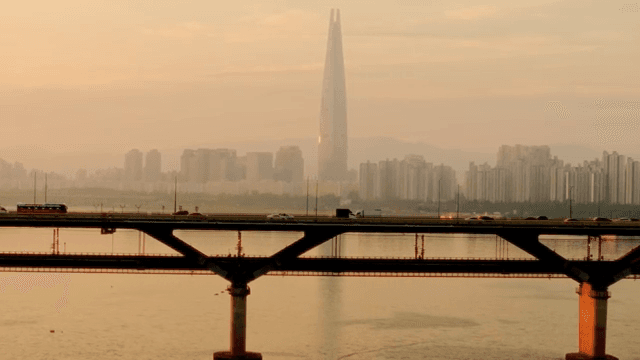 Bridge over a river with a city skyline at sunset