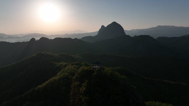 햇빛이 비치는 울창하고 푸른 산봉우리 위 정자