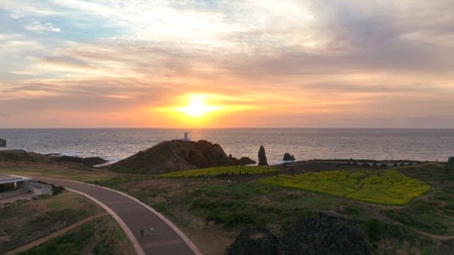 Sunset over a coastal landscape with a lighthouse