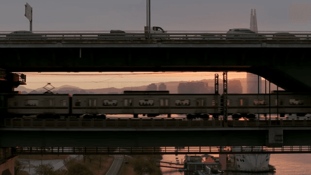 City bridge with cars and train at sunset