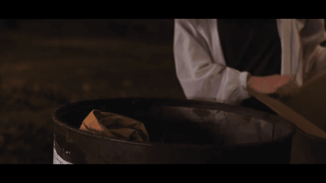 드럼통 속에 상자 속 물건을 집어넣는 여성