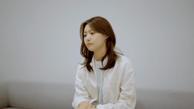 소파에 앉아 초조하게 무언가를 기다리는 여성