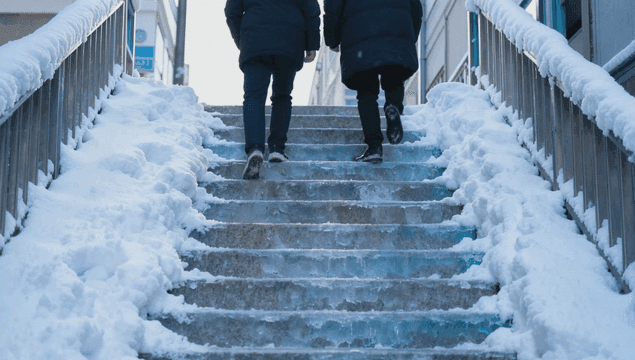 Backs of two people climbing snow-covered stairs