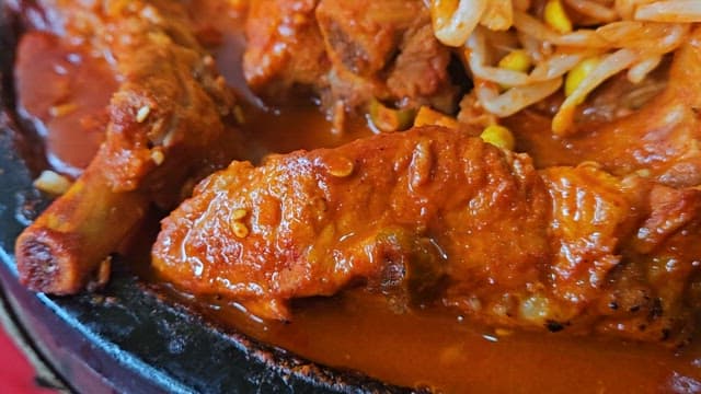 뜨거운 접시에 담긴 매운 돼지갈비찜과 콩나물