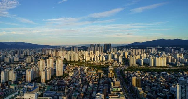 Busy scene and sky in downtown Daegu with densely packed buildings from midday to night