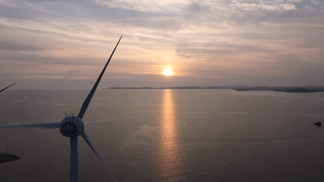 Sunset over the ocean with wind turbines