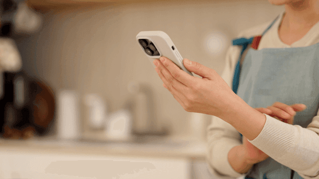 Housewife using smartphone in kitchen