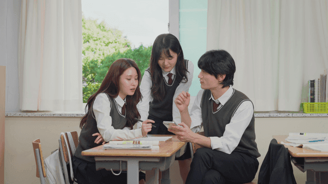 교실에서 모여 휴대폰을 보며 잡담하는 학생들