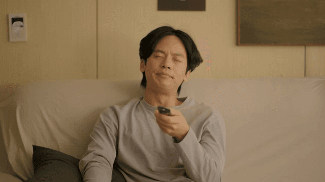 리모컨을 들고 소파에 앉아 있는 남자