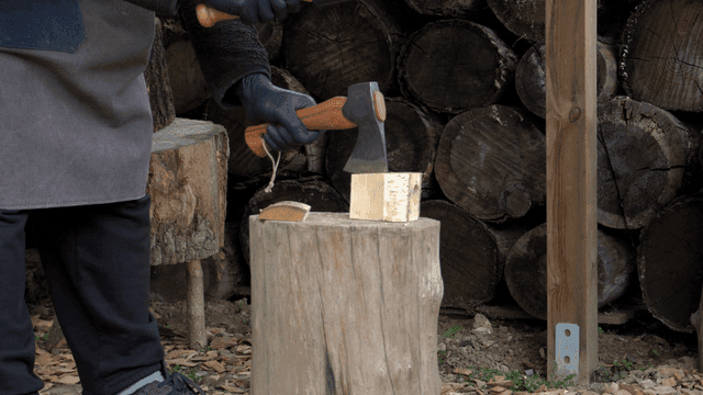 야외에서 도끼로 나무를 패는 모습