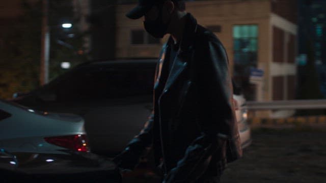 Man Taking Out a Large Bag from the Trunk at Night