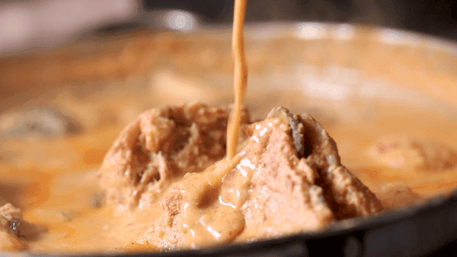Rich broth being poured over meat
