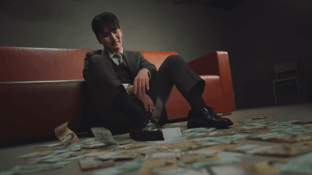 돈과 함께 바닥에 앉아 있는 정장 남성