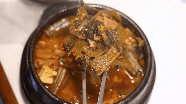 Chopsticks lifting gatgimchi stew with tofu and pork