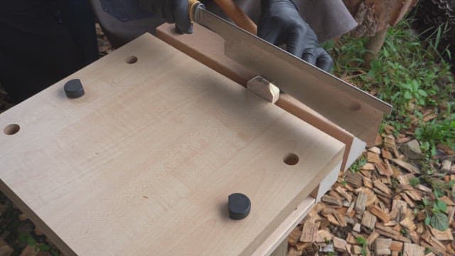 야외에서 톱으로 나무를 깎는 사람