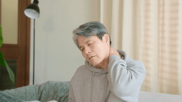 실내에서 목을 잡고 앉아 있는 노인