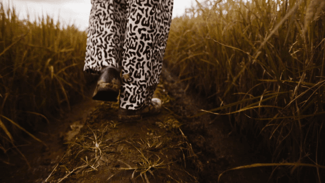 Old student walking along field path with muddy shoes