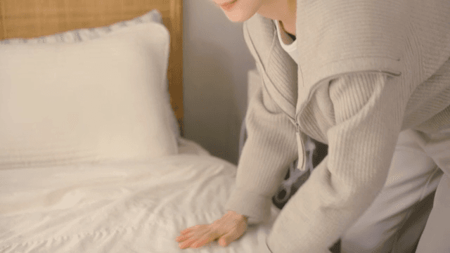아늑한 방에서 침대를 정리하는 여성