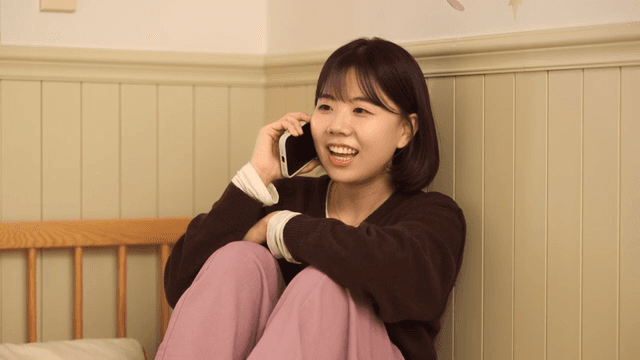 Young woman talking on phone and looking at her smartphone in her room