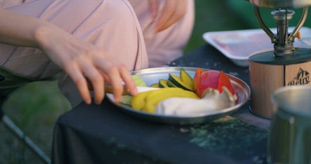 Hands Preparing Fresh Vegetables at Campsite