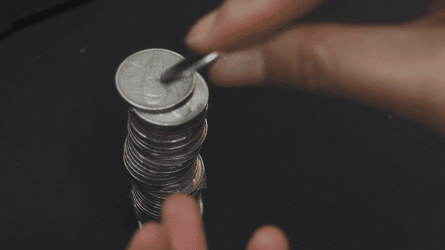 검은 책상 위에 동전 쌓는 손