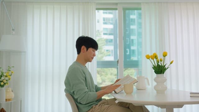 Man Reading a Book by the Window in Bright Living Room