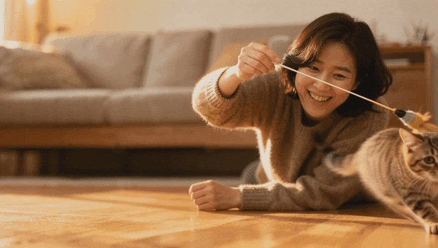 집 거실에서 고양이와 놀고 있는 여성