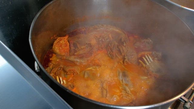 Meat being boiled in a large steaming pot