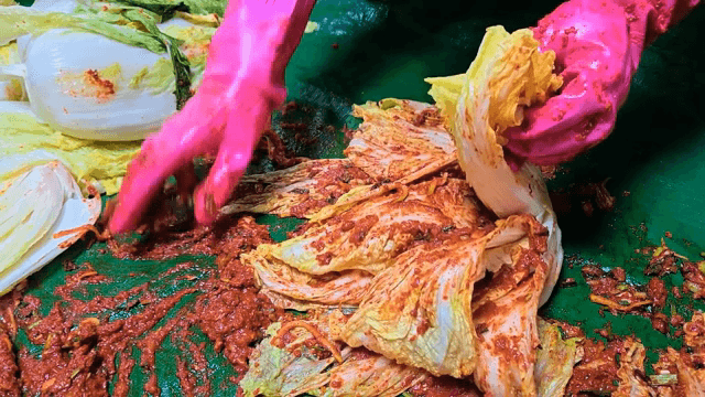 Kimchi being prepared with seasoning
