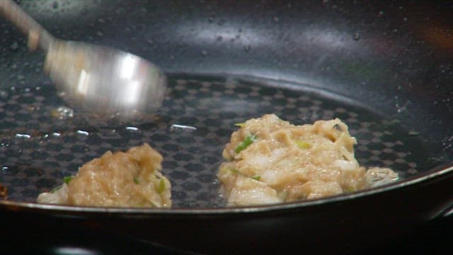 Cooking the batter of donggeurangtang in an oiled frying pan with a spoon