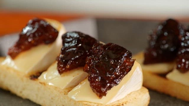 전채 요리를 위해 치즈에 가니쉬를 올리는 손