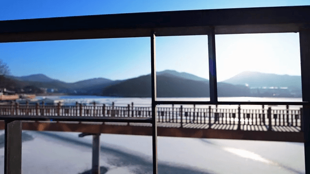 다리 위에 걸어가면서 찍은 얼어붙은 강 위의 다리와 산