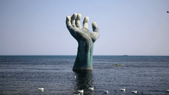 갈매기와 함께 바다에 있는 큰 손 조각상