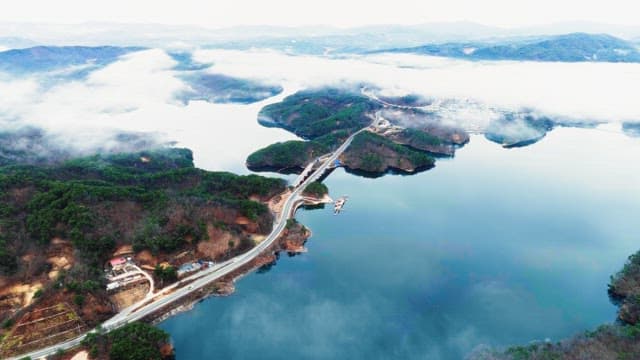 Aerial View of Village and Road Over Foggy Lake