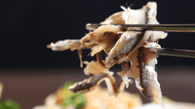 Raw anchovies picked up with chopsticks