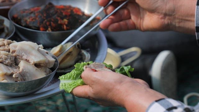 Preparing Korean lettuce wraps with fresh abalone and meat