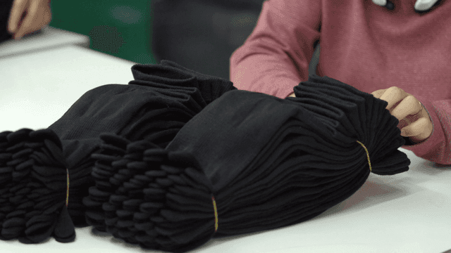 Worker arranging black socks on table
