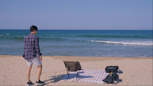 바닷가에 돗자리를 깔고 앉아 사색하는 남자