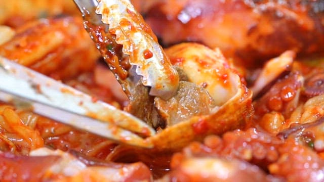 Taking out meat from conch in spicy braised seafood