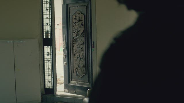 가정집의 현관문을 닫고 들어와 쇼파에 앉는 여자