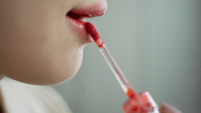어플리케이터로 입술에 빨간색 틴트를 바르는 모습
