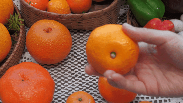 Hands selecting fresh tangerines on display