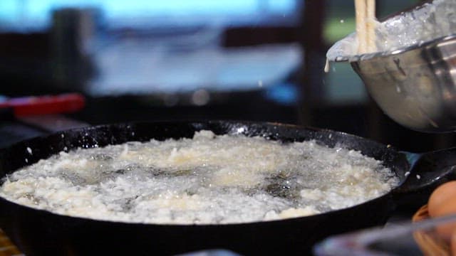 Batter being poured into hot oil for frying