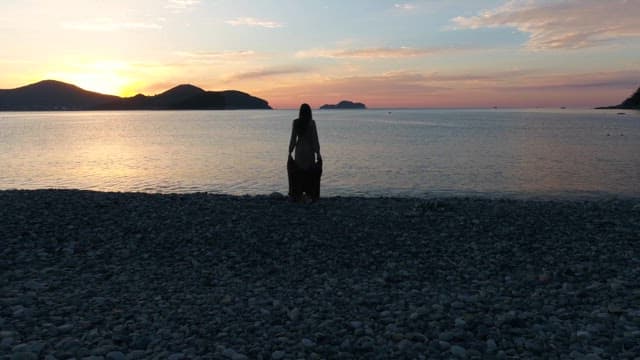 바다 위로 저무는 해를 바라보고 선 여자의 뒷모습