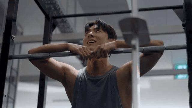 헬스장에서 운동 중 바벨에 기대어 휴식하는 남성